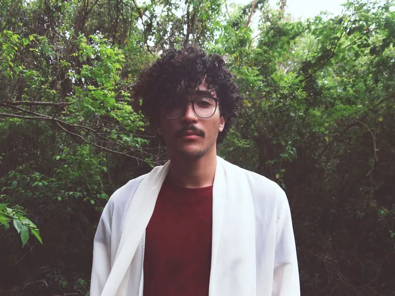 Curly cut and glasses in a green thicket