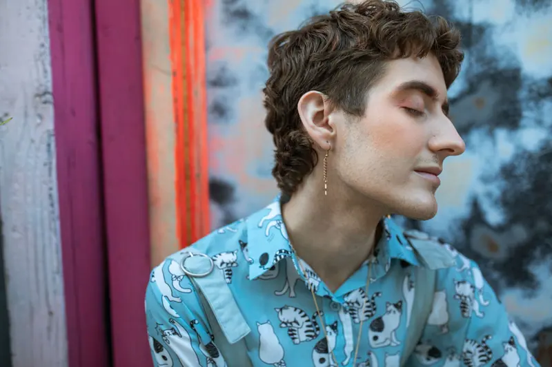 Short curls and a printed shirt against a painted wall