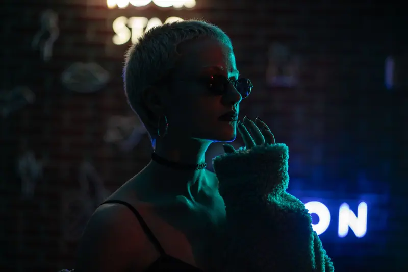 Portrait of a fashionable woman posing in a nightclub with neon lights.