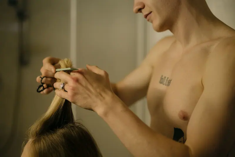 Stylist trimming long blonde hair in low light