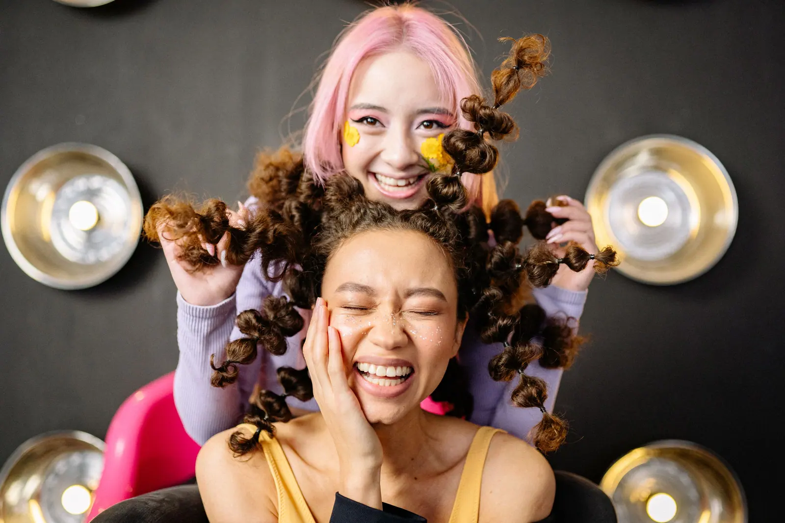 Cheerful young models posing indoors with creative hairstyles and makeup in a modern setting.