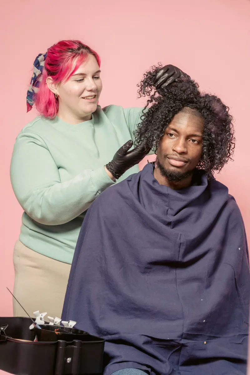 Stylist shaping a client's curls in the pink room