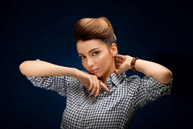 Elegant portrait of a young woman in a checkered shirt looking confidently at the camera.
