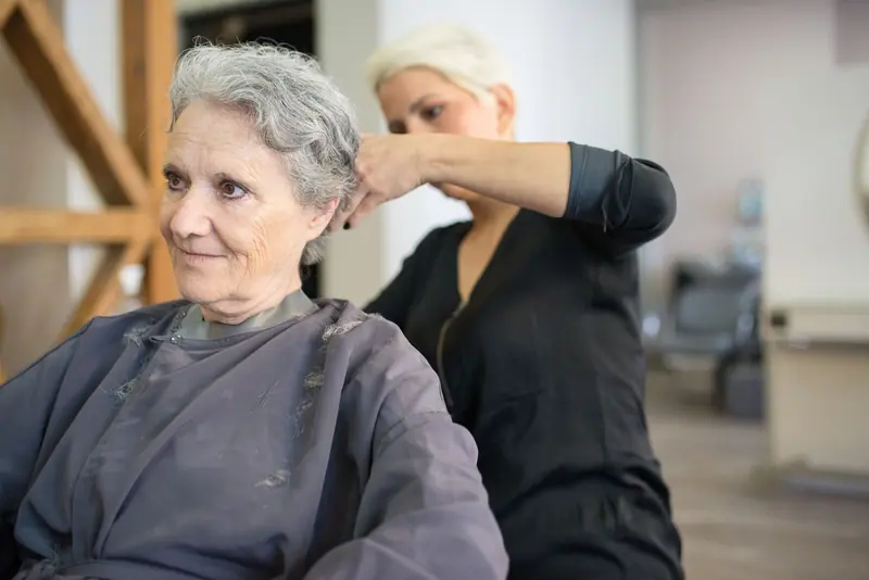 Stylist cutting an older client's silver hair