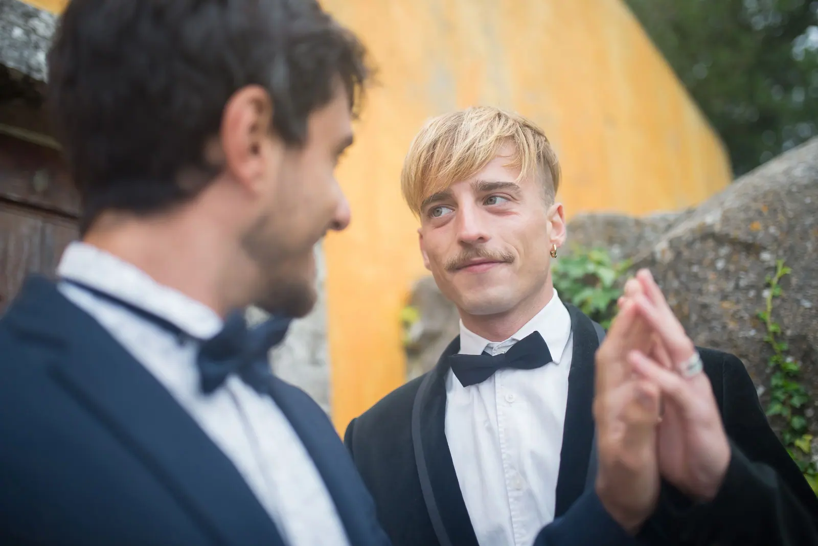 A touching moment between two grooms in a picturesque outdoor wedding setting in Portugal.