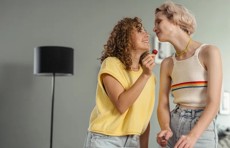 Two friends laughing over a lollipop
