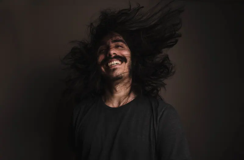 Laughing mid hair-flip in low light