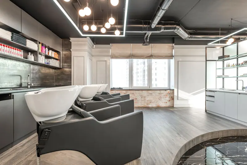 Spacious, contemporary salon interior with styling chairs, shelves, and lighting.