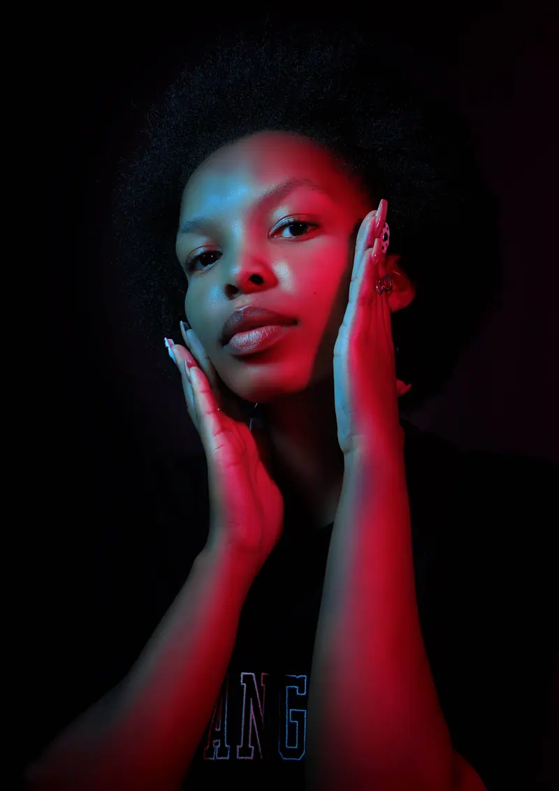 Dramatic studio portrait with red and blue lighting effects on a woman with natural hair.
