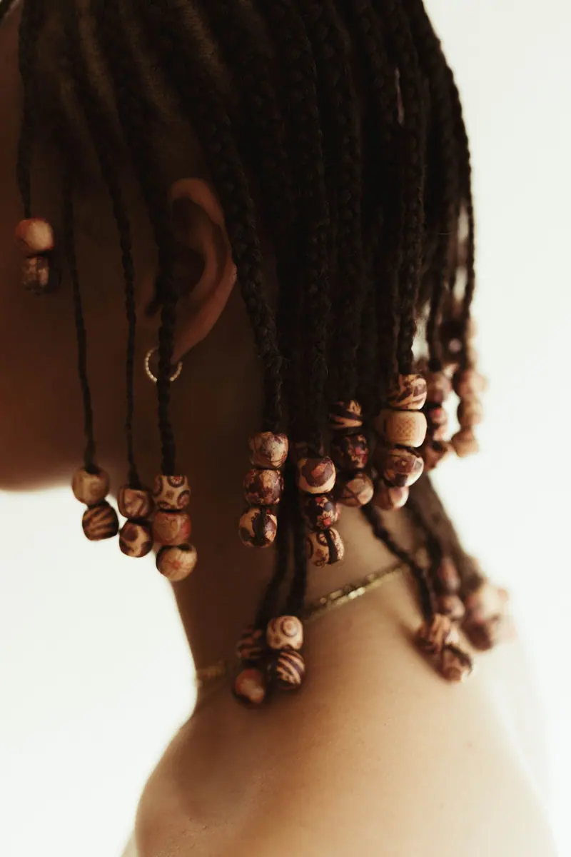 Elegant afro braids adorned with wooden beads, showcasing intricate hair styling.