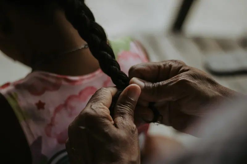 Close-up of hands braiding a young girl's hair, creating a connection between generations.