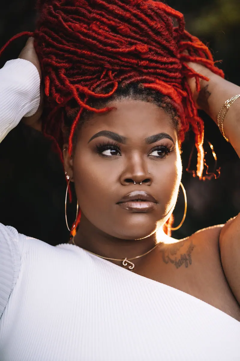 Woman with red locs and gold hoop earrings