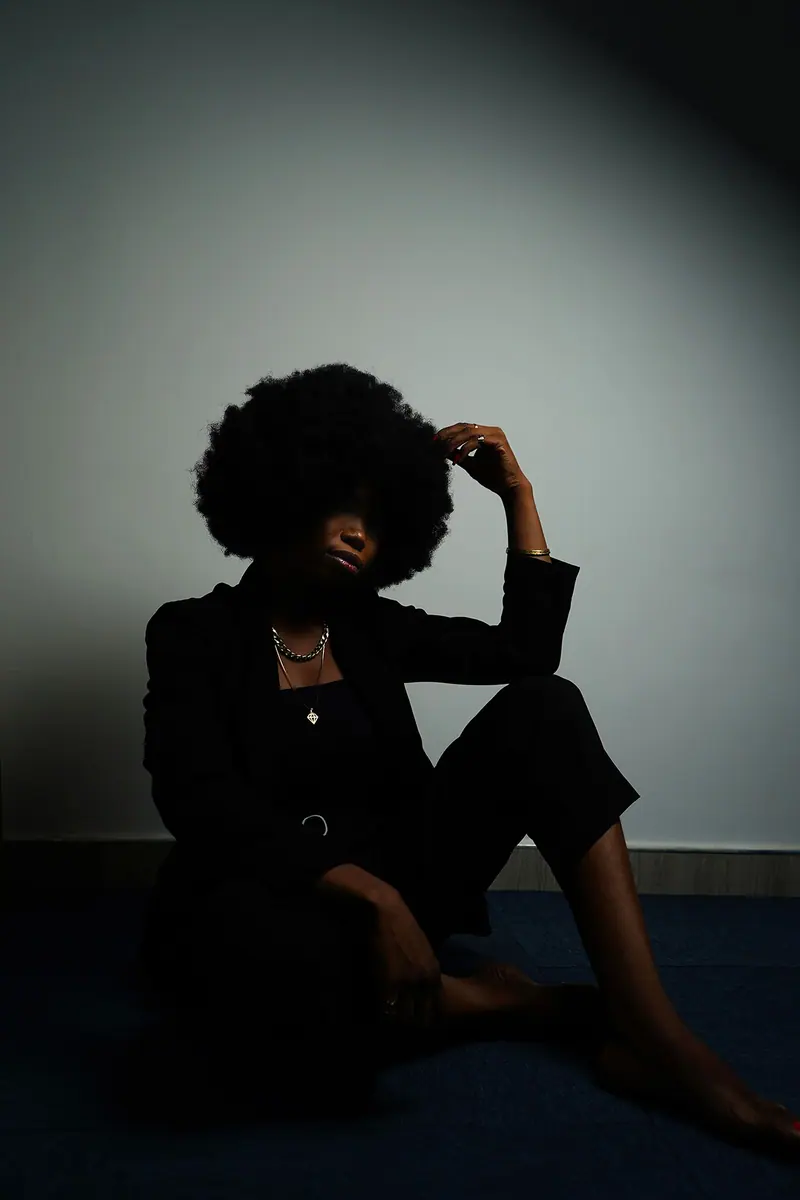 Striking portrait of a woman with an afro hairstyle in a studio setting.