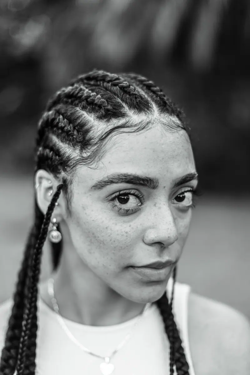 Close-up black and white portrait of a woman with braided hair, showcasing natural beauty and confidence.