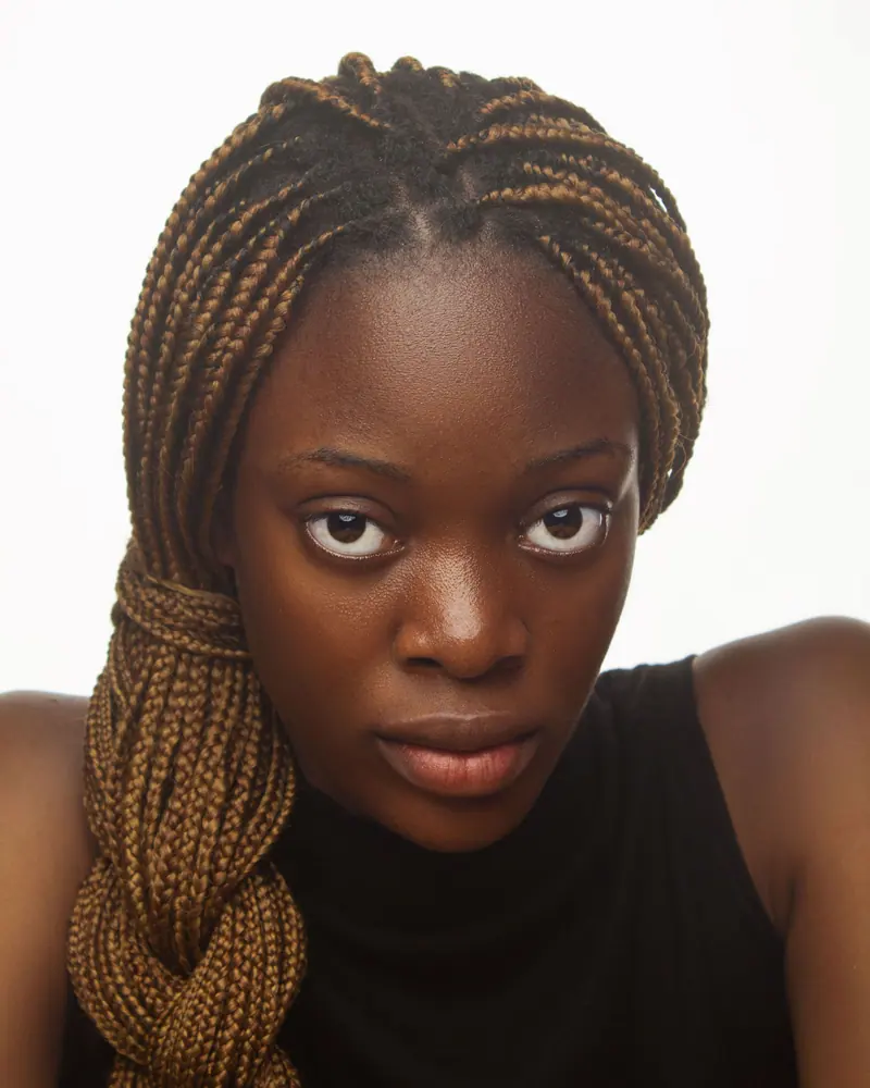 Close-up portrait of a black woman with braided hair against a neutral background.