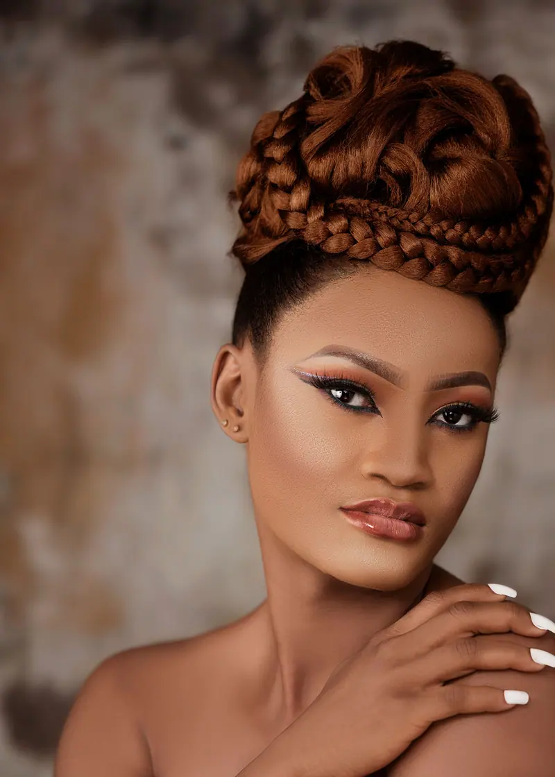 Sophisticated studio portrait featuring woman with intricate braided hairstyle, showcasing elegance and glamour.