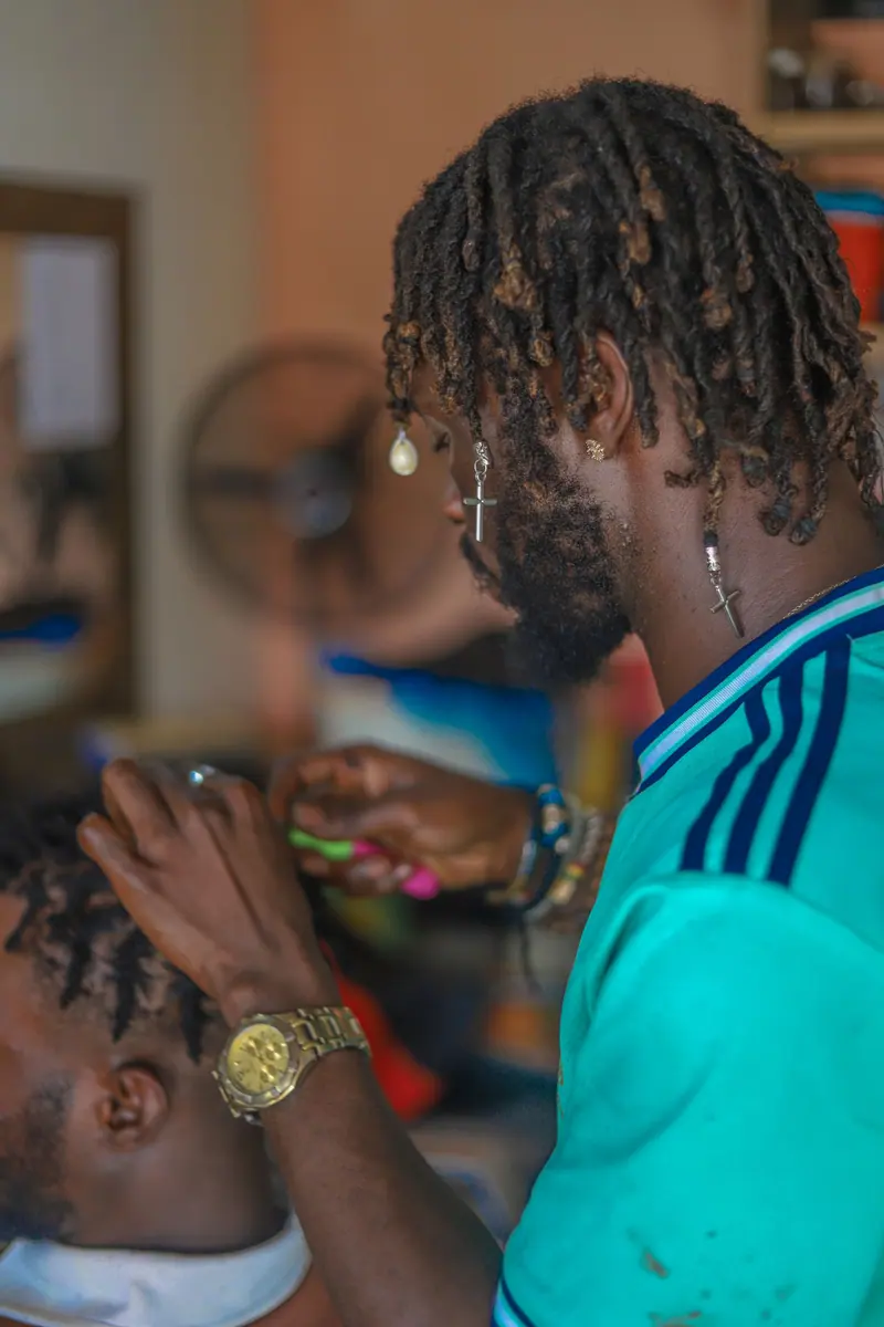 Barber skillfully styles dreadlocks for a client in a contemporary barbershop setting.