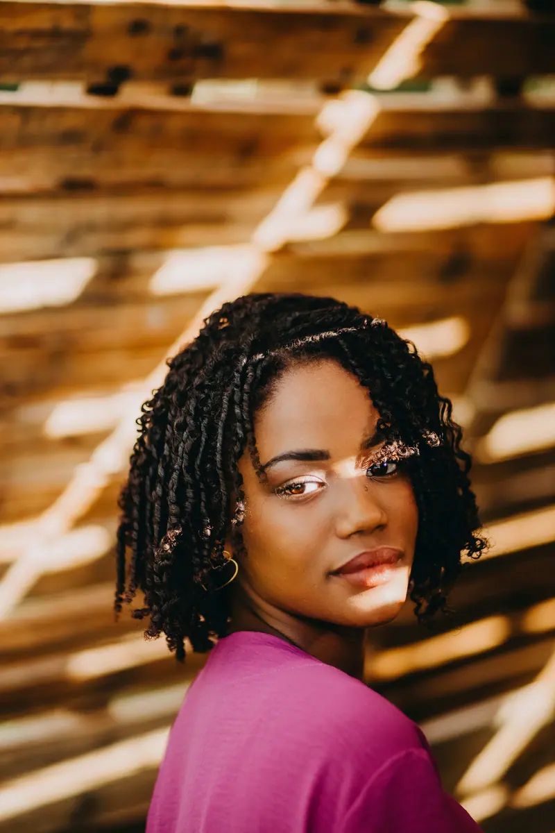 Elegant portrait of a woman with natural hairstyle illuminated by outdoor sunlight.