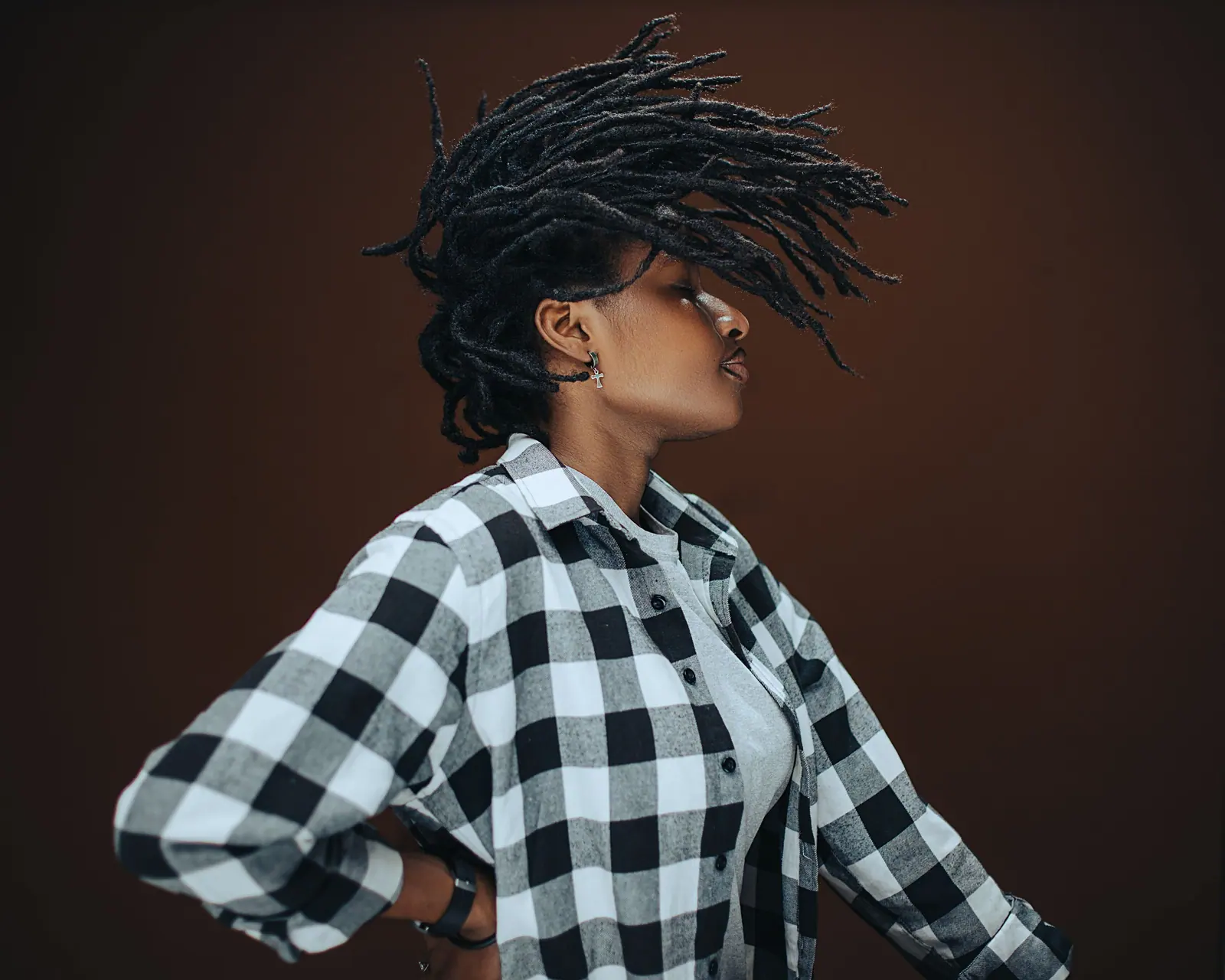 Woman with long locs tossing her hair in a warm studio