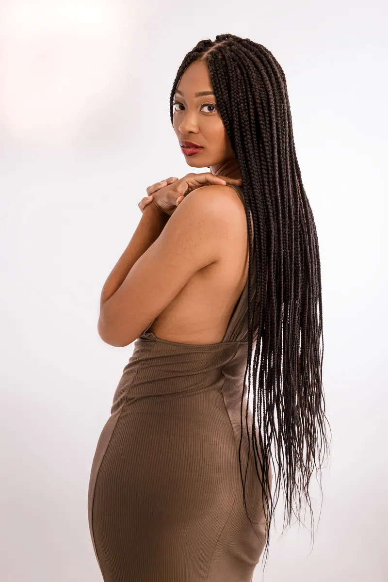 Graceful pose of an African American woman with long braids in a studio setting.