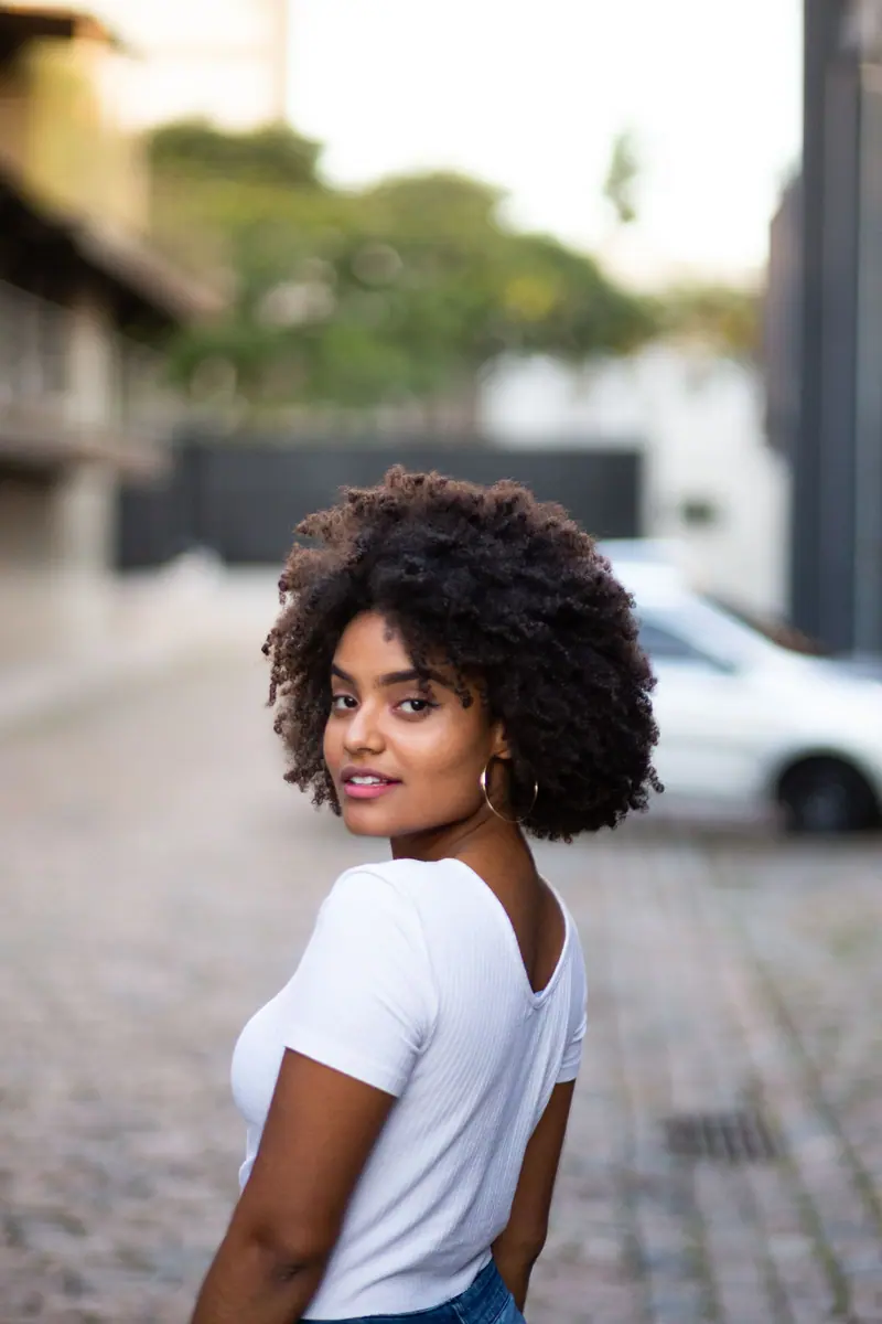 Portrait of a stylish young black woman with curly hair posing outdoors.