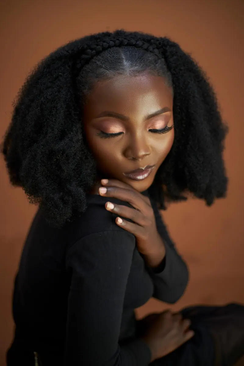 Portrait of a woman with natural afro hairstyle and elegant makeup indoors.