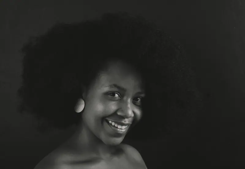Monochrome close-up portrait of a smiling woman with afro hairstyle.