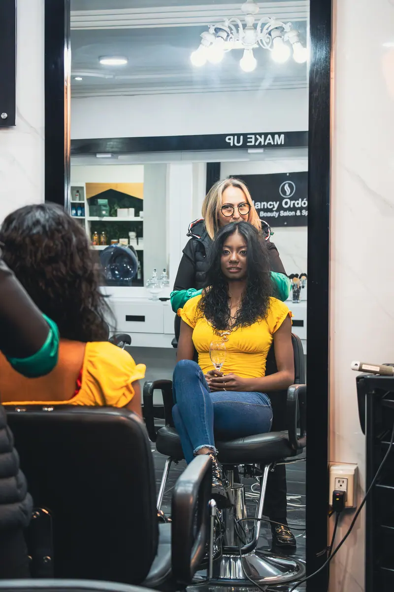 A woman getting a hair treatment in a salon, looking in the mirror.