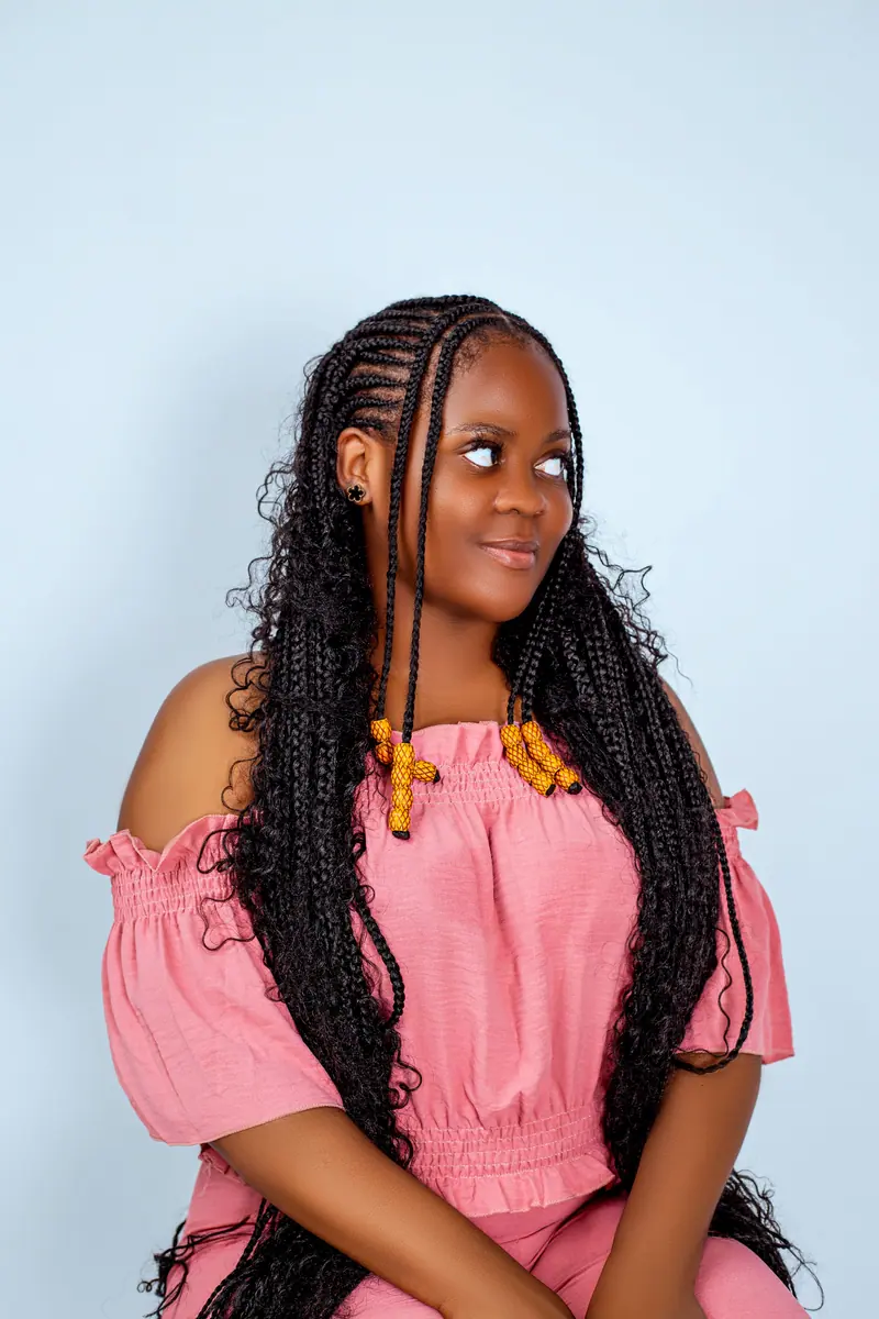 Smiling client with long boho braids in a pink off-shoulder top