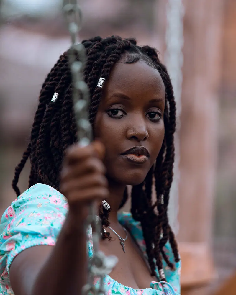 Portrait of a woman with natural hairstyle sitting on a swing outdoors.