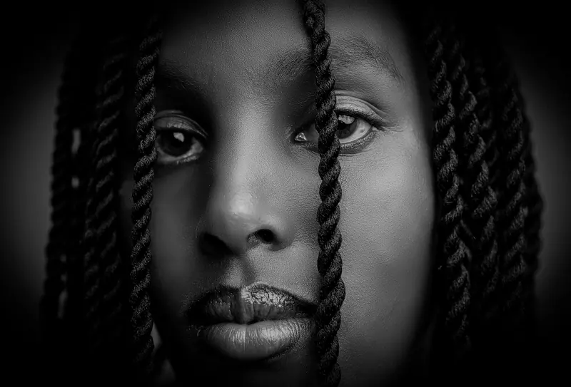 Close-up black and white portrait of a woman with braided hair.