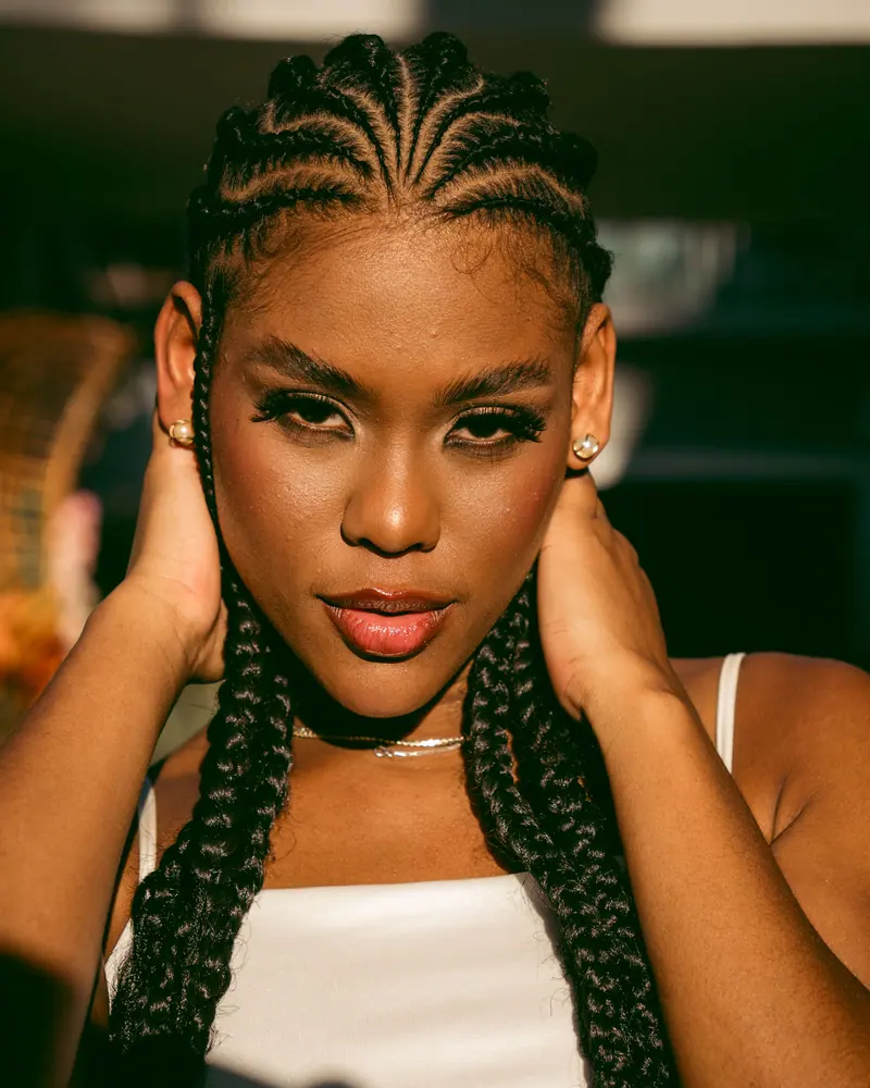 Stunning close-up portrait of a woman with braided hair, captured in warm sunlight revealing vibrant details.