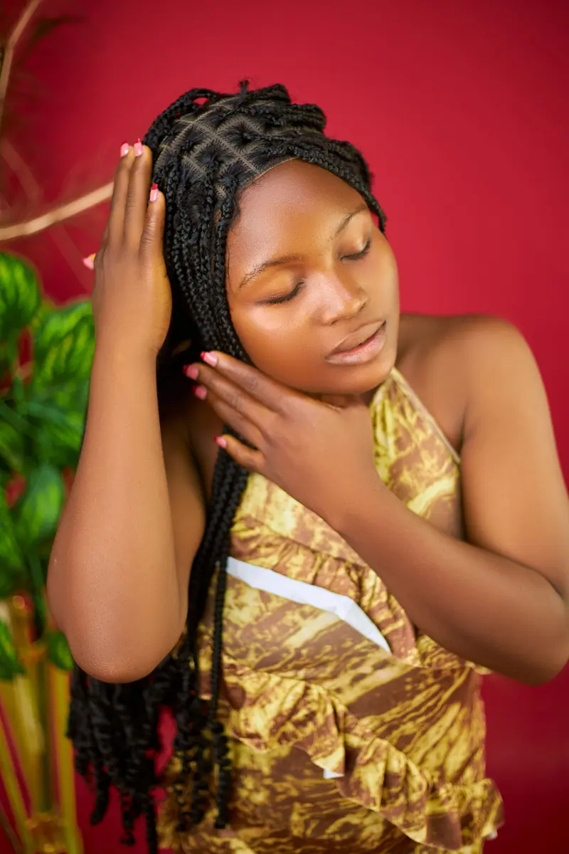 Elegant portrait of a woman with braided hair against a red background.