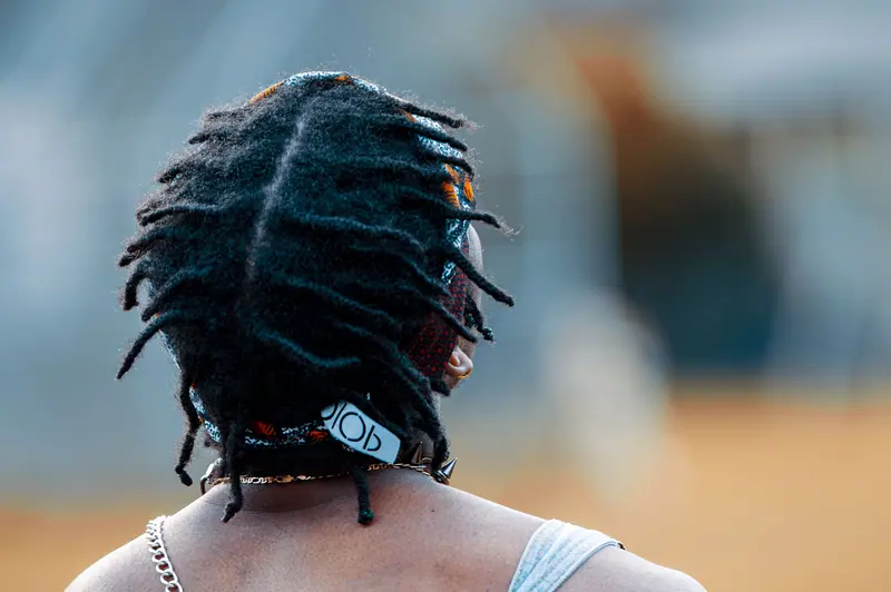 A man with dreadlocks and a bandana in an urban environment, showcasing modern street style.