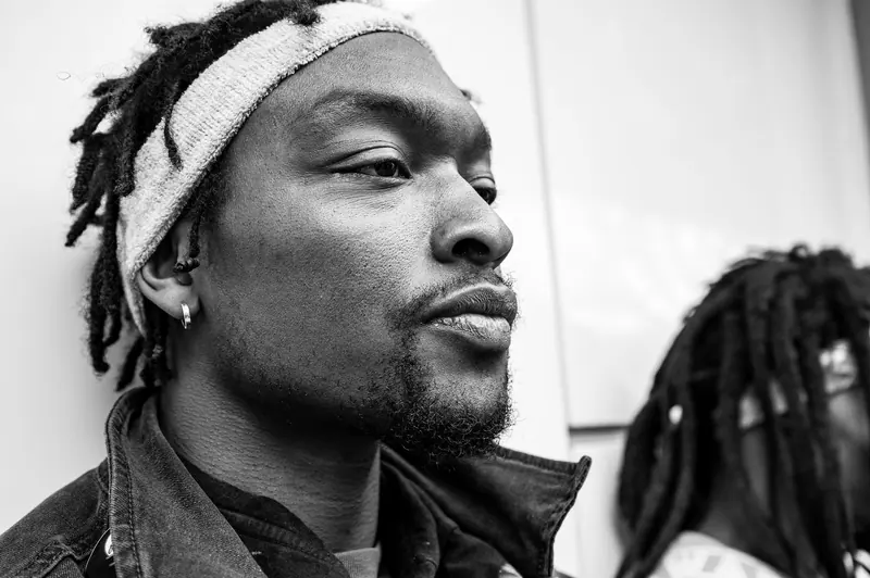 Monochrome close-up portrait of a pensive man with dreadlocks, expressing deep contemplation.