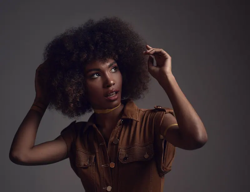 Studio portrait of a beautiful black woman with curly hair, showcasing fashion and elegance.