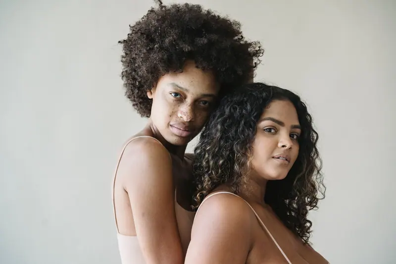 Two women embracing in a studio, highlighting diversity and body positivity.