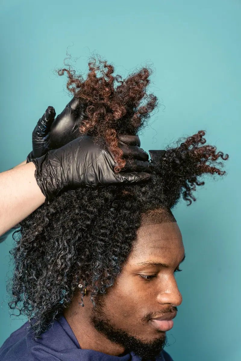 Professional hairstylist working on natural hairstyle for a male client in studio setting.
