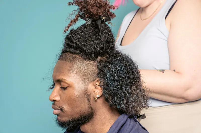 Expert hairstylist working on a man's unique hairstyle in studio setting.