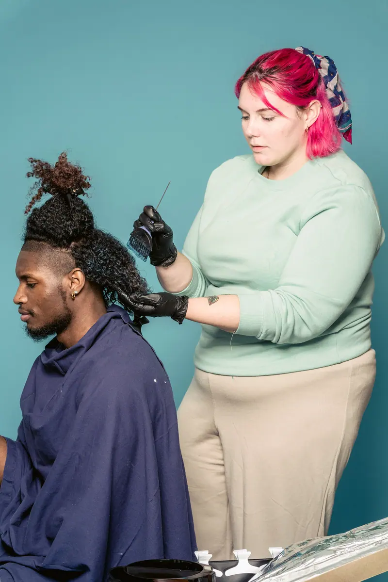 Hairdresser working on an afro hairstyle indoors with focus and precision.
