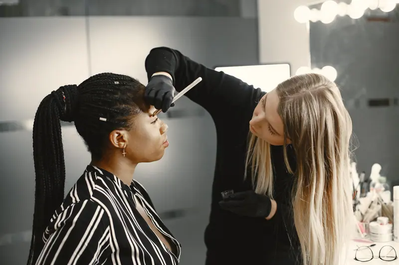 Makeup artist applies makeup to a client in a modern studio setting.