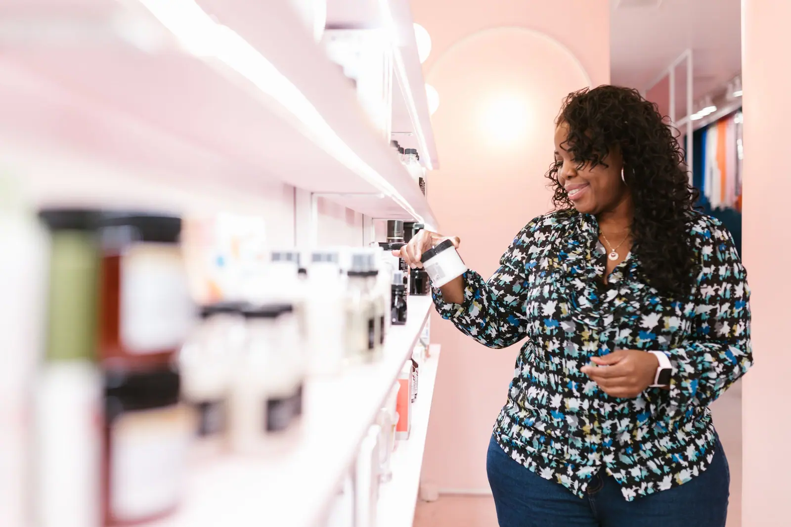 Smiling woman browsing beauty products on store shelves.