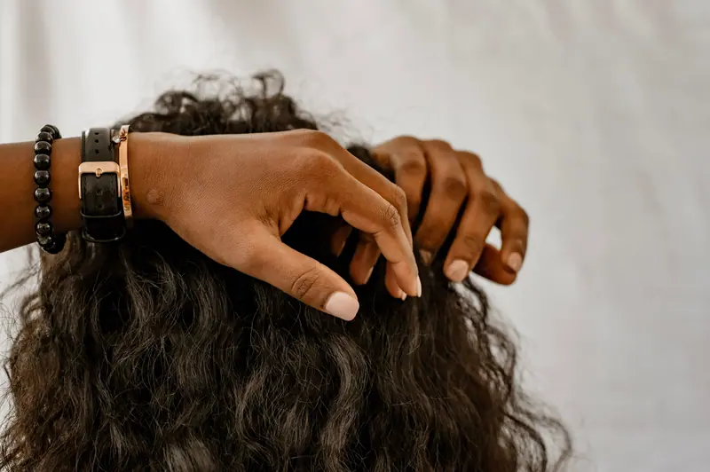 Detailed image of hands styling curly hair, showcasing accessories and a natural hairstyle.