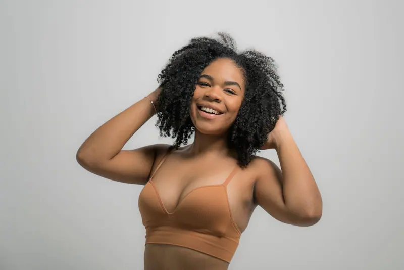 Joyful African American woman with curly hair posing in a studio setting.
