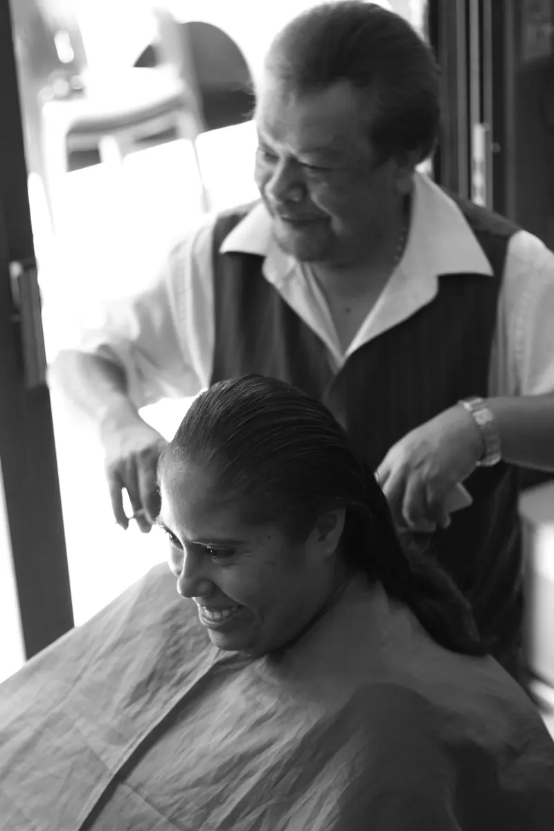 Smiling woman getting a haircut in black and white small business barber shop.