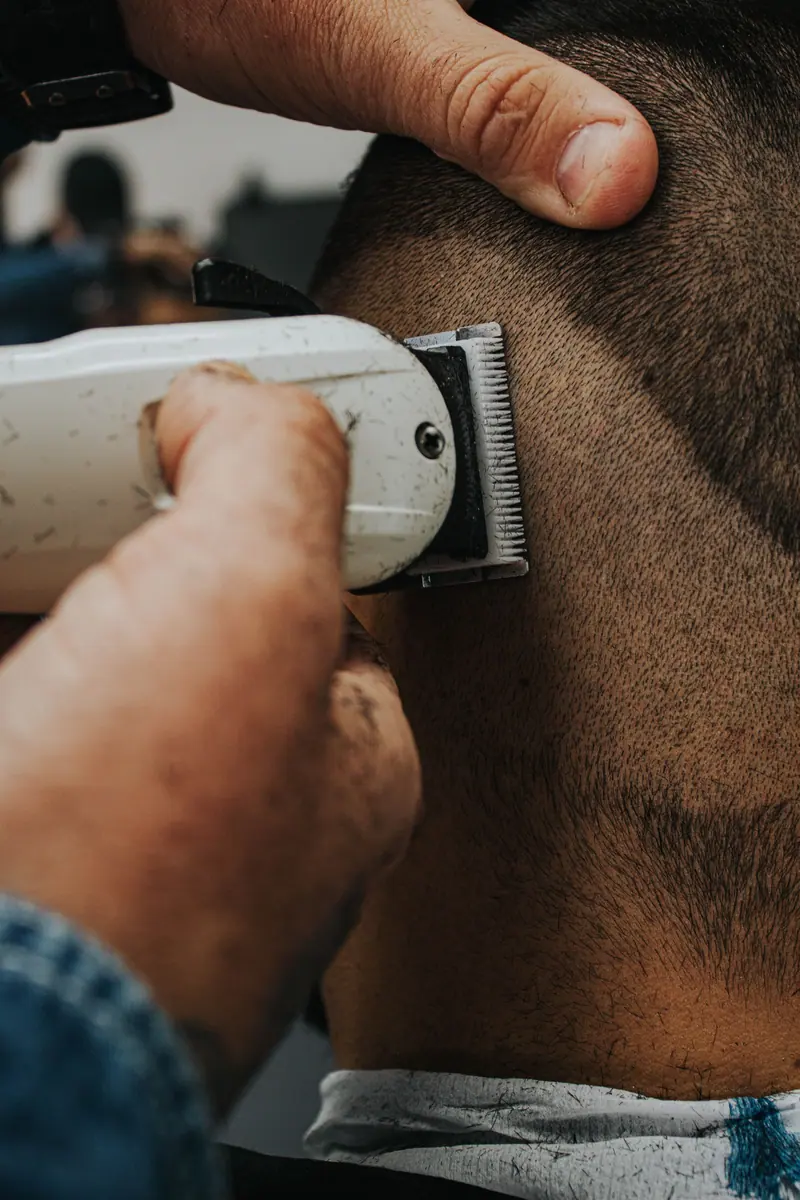 Close-up view of a barber using an electric shaver on a client indoors.