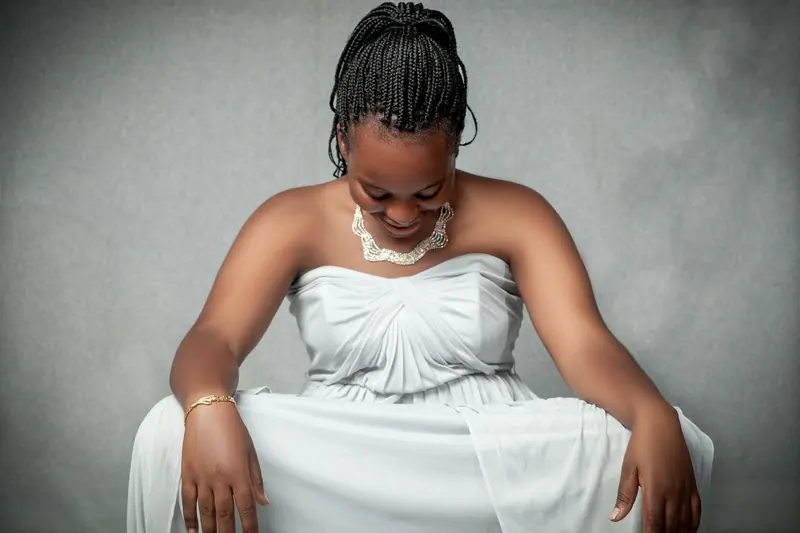 Elegant portrait of a woman in a white dress, looking downward with a graceful smile.
