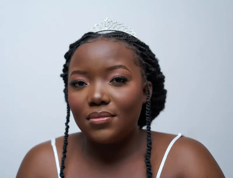Elegant bride with braided hair and tiara, captured indoors in Lusaka.