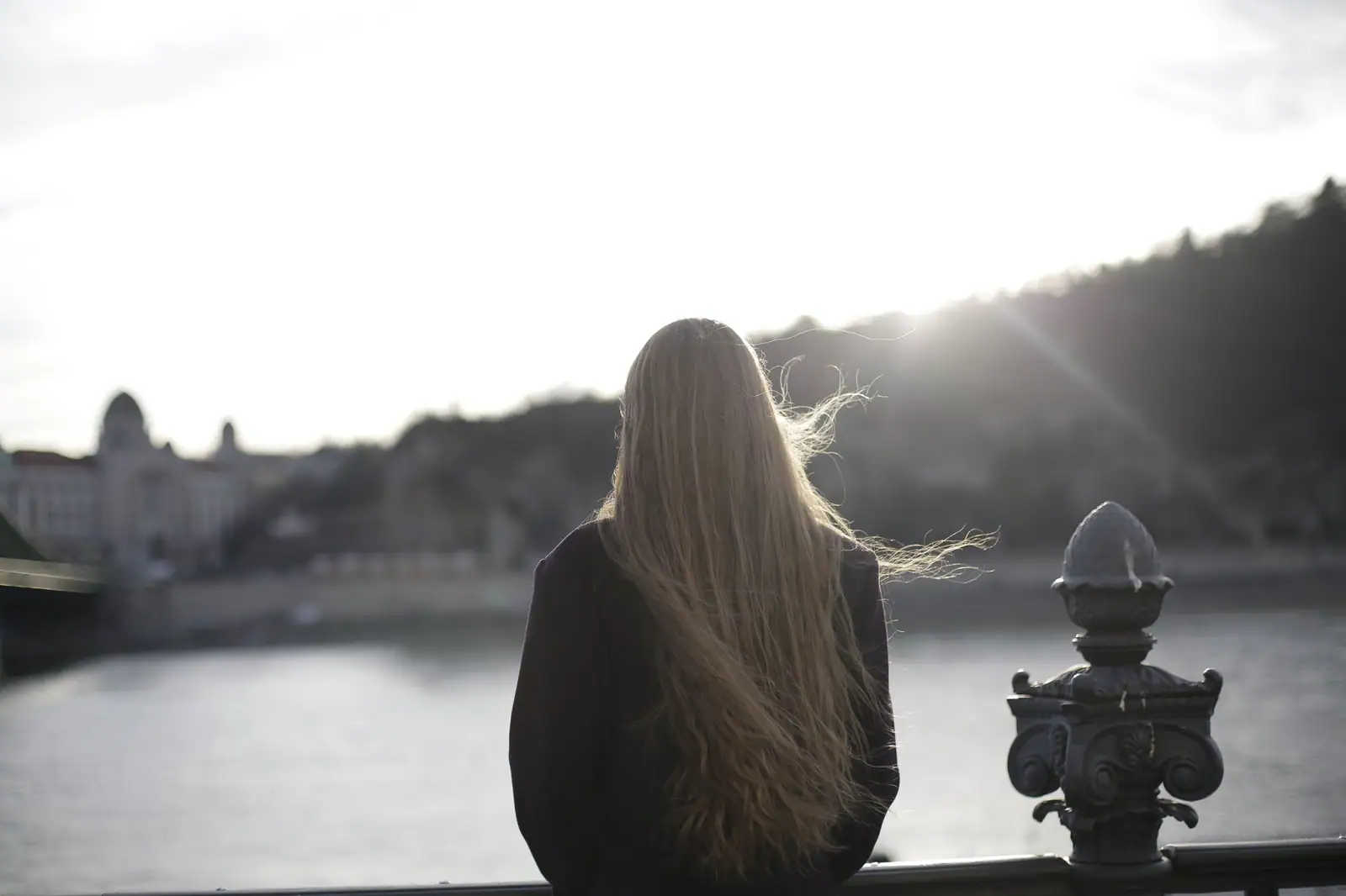 Long blonde lengths catching the evening light, seen from behind on a river walk