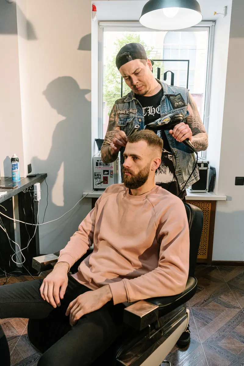 A bearded man receives a haircut from a skilled barber in a trendy barbershop.